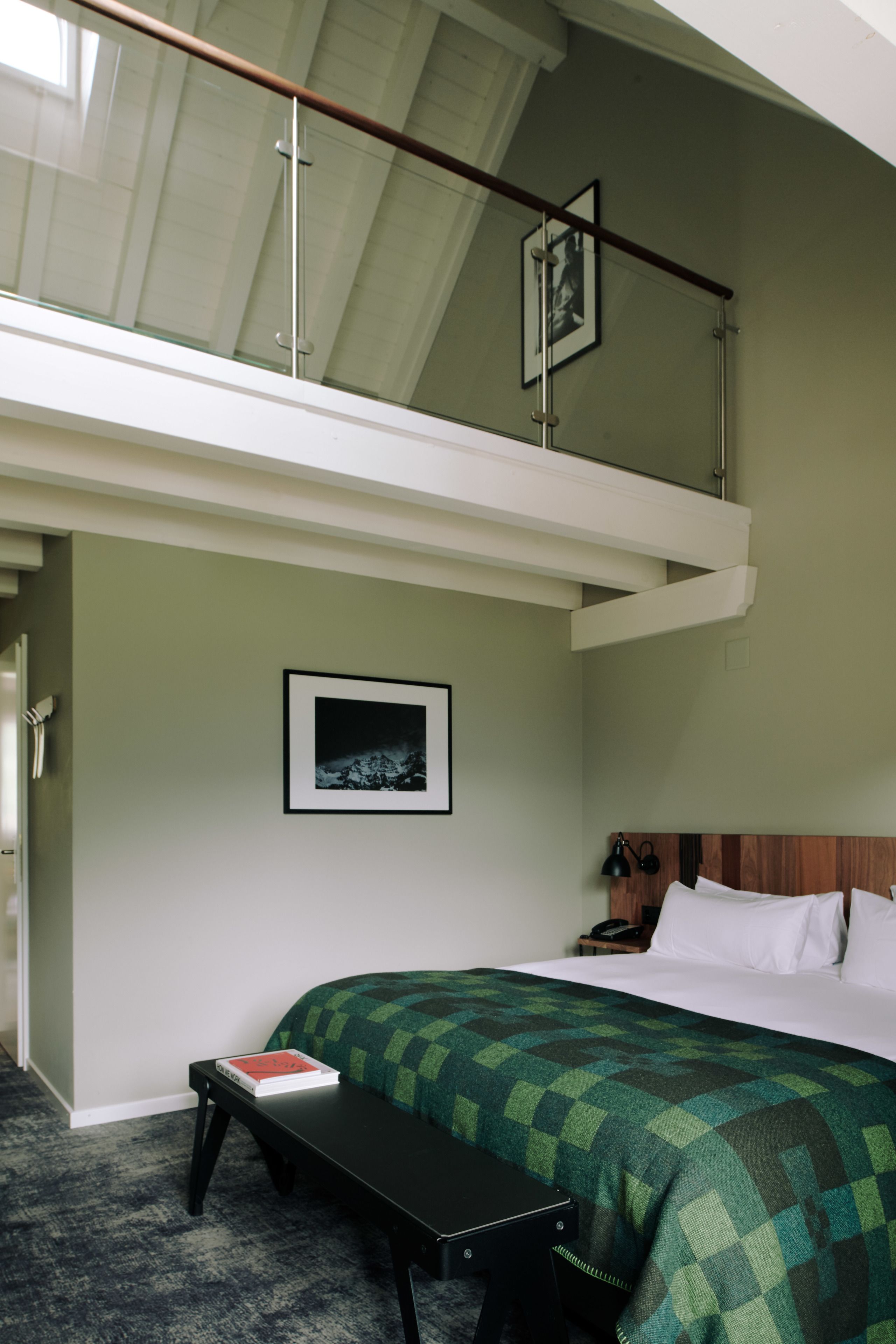 Een slaapkamer met een bed, een bankje, een nachtkastje en een foto aan de muur.