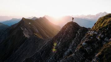Een bergachtig landschap met een persoon op een bergtop.