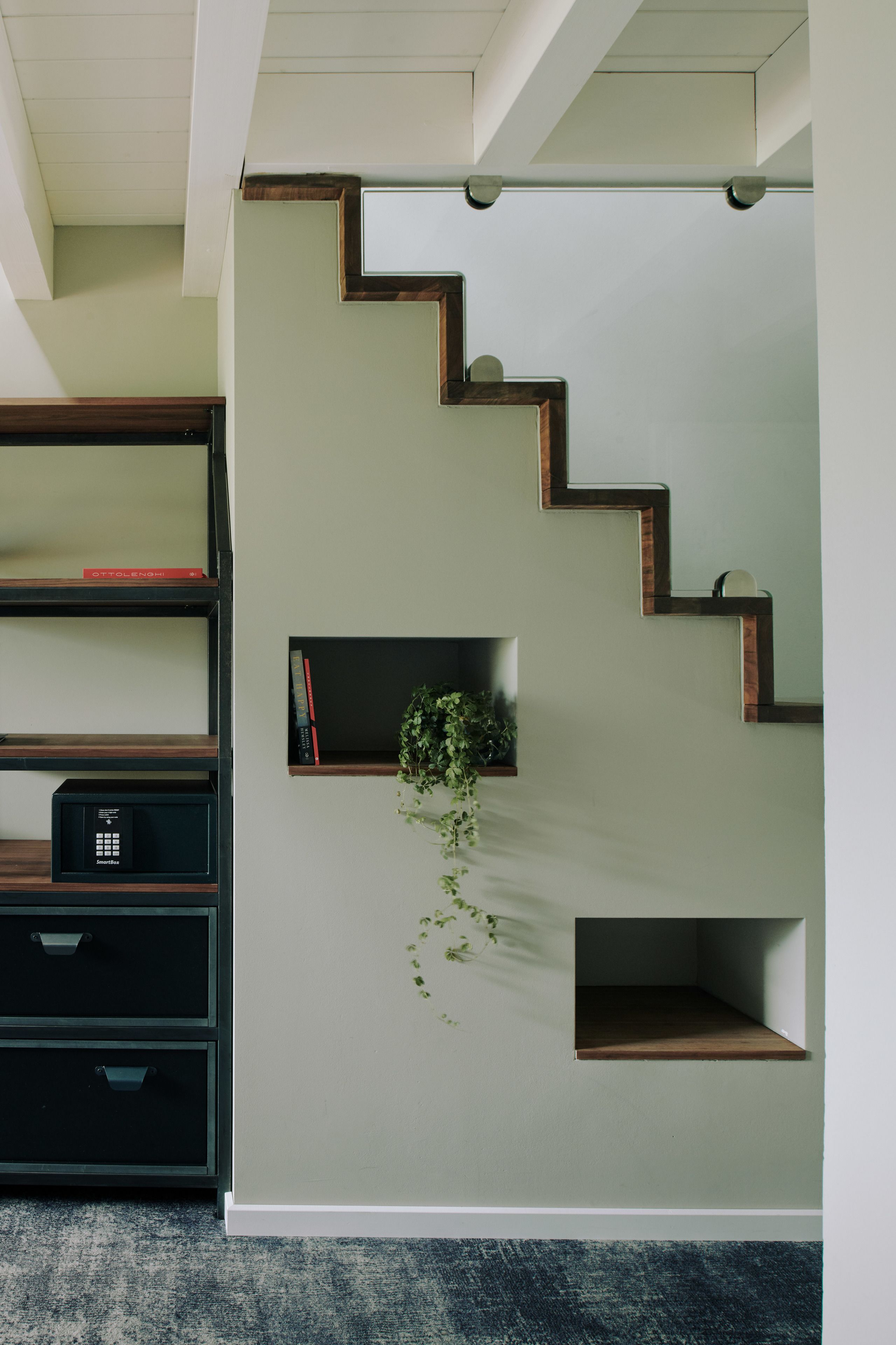 Ein modernes Interieur mit Treppe, Einbauschränken und einer kleinen Pflanze.