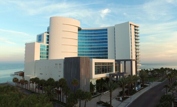 A modern hotel with a curved facade, large windows, and a view of the sea. - Opal Sands Resort (Clearwater Beach)