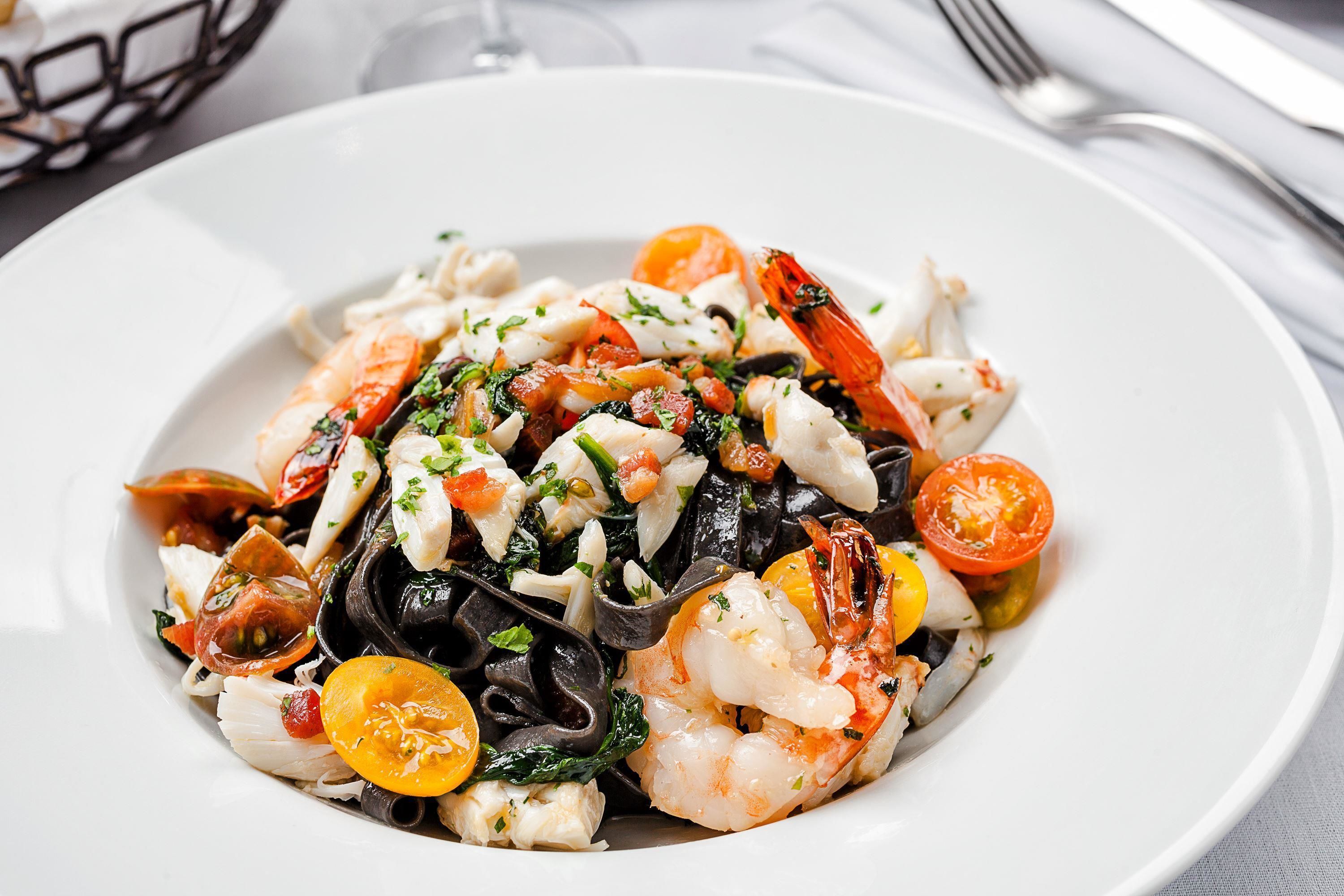 A plate of seafood pasta with shrimp, mussels, and cherry tomatoes.