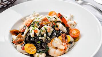 A plate of seafood pasta with shrimp, mussels, and cherry tomatoes.