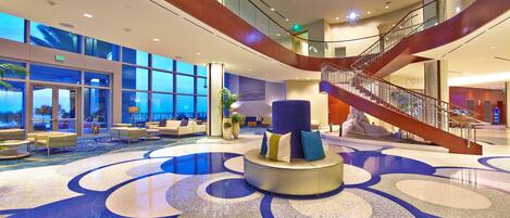 A spacious lobby with a central seating area, a staircase, and large windows offering views.