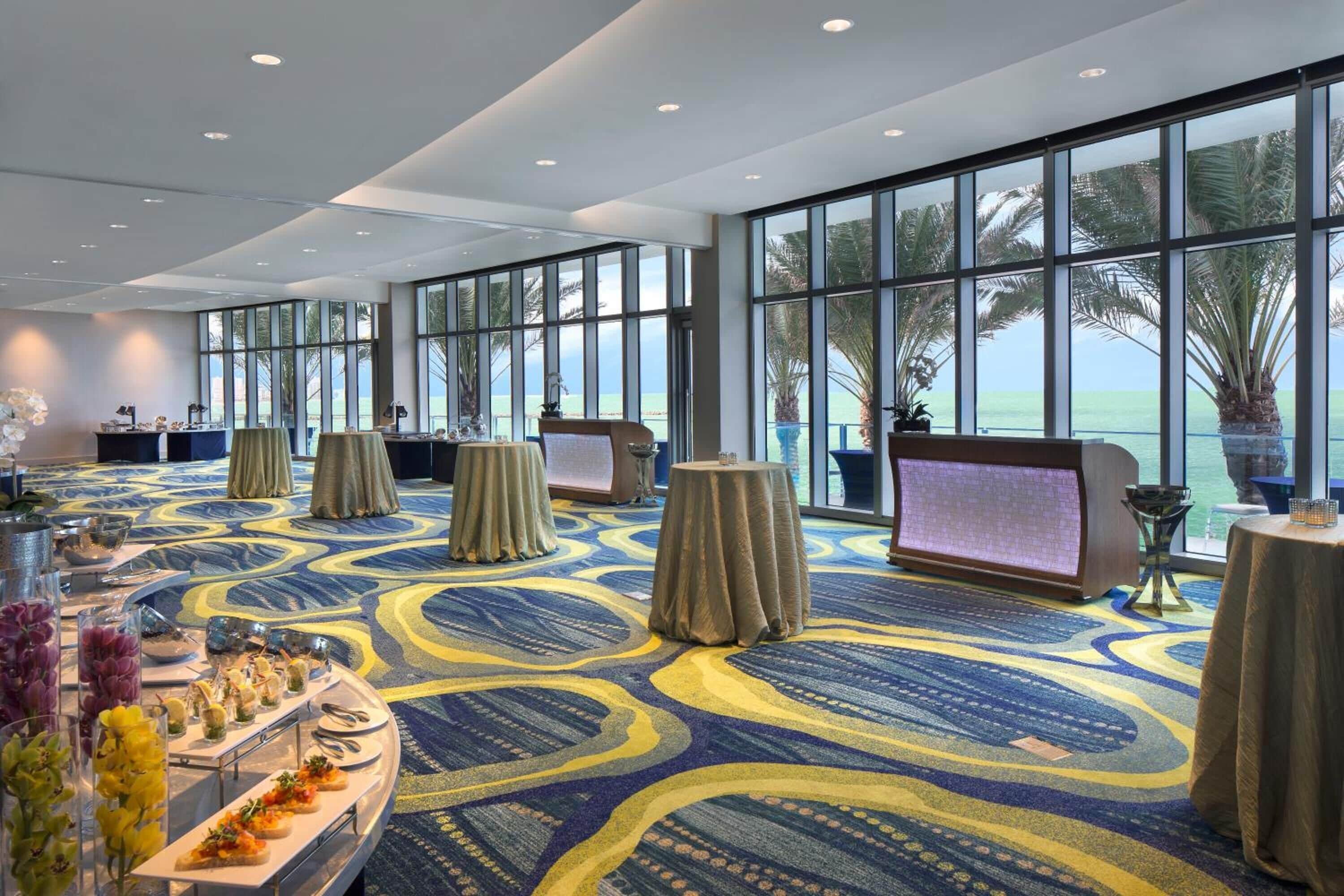 A spacious conference room with large windows, a patterned carpet, and a buffet table with various food items.