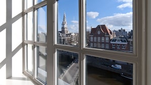 Blick durch ein Fenster mit mehreren Fensterscheiben auf eine Stadtansicht mit historischen Gebäuden und einem markanten Turm.