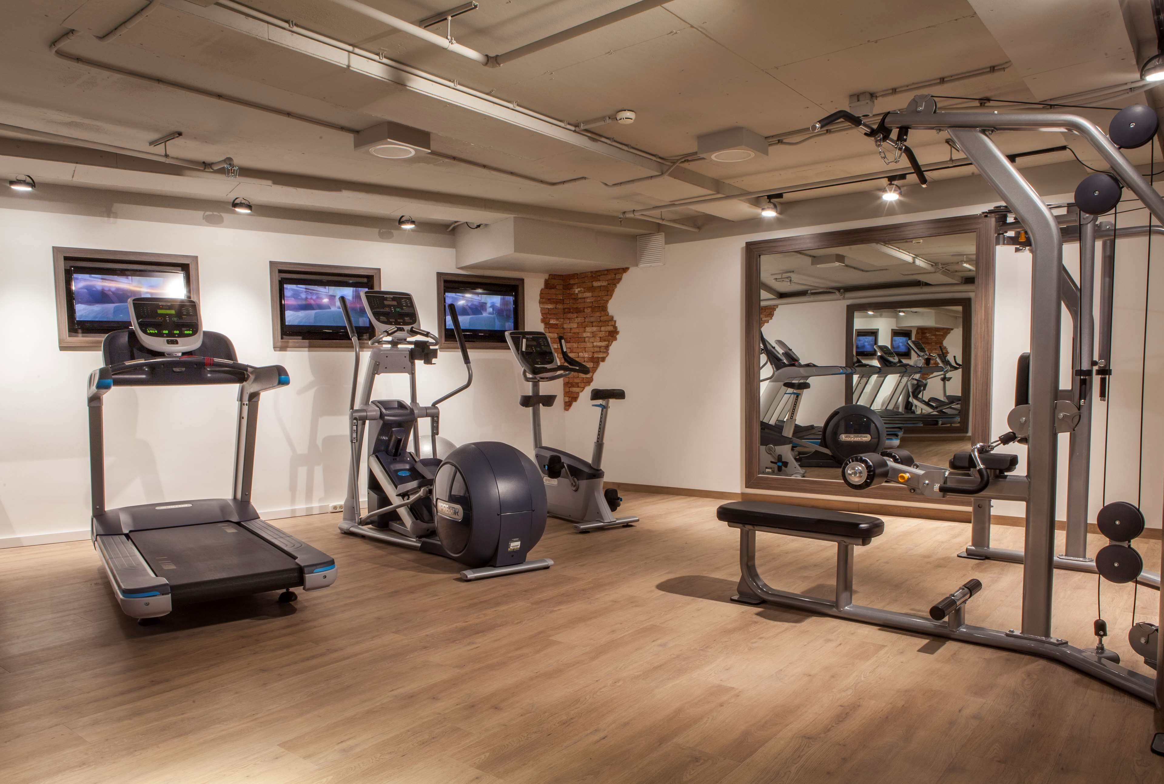 Un gimnasio con cintas de correr, elípticas, una bicicleta estática y equipo de levantamiento de pesas.