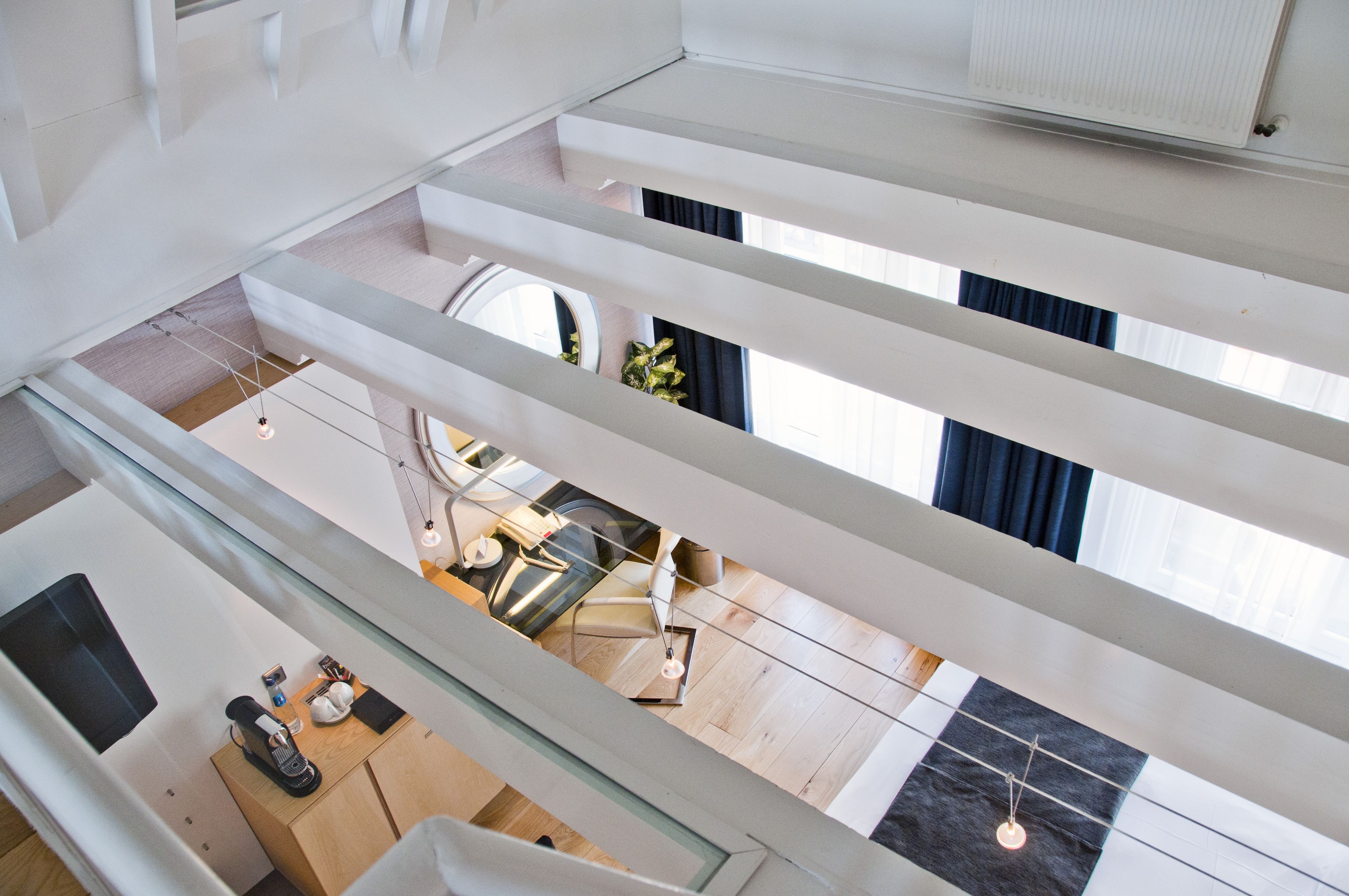 Ein modernes Interieur mit hoher Decke, einer Treppe und einem Essbereich mit Tisch und Stühlen.