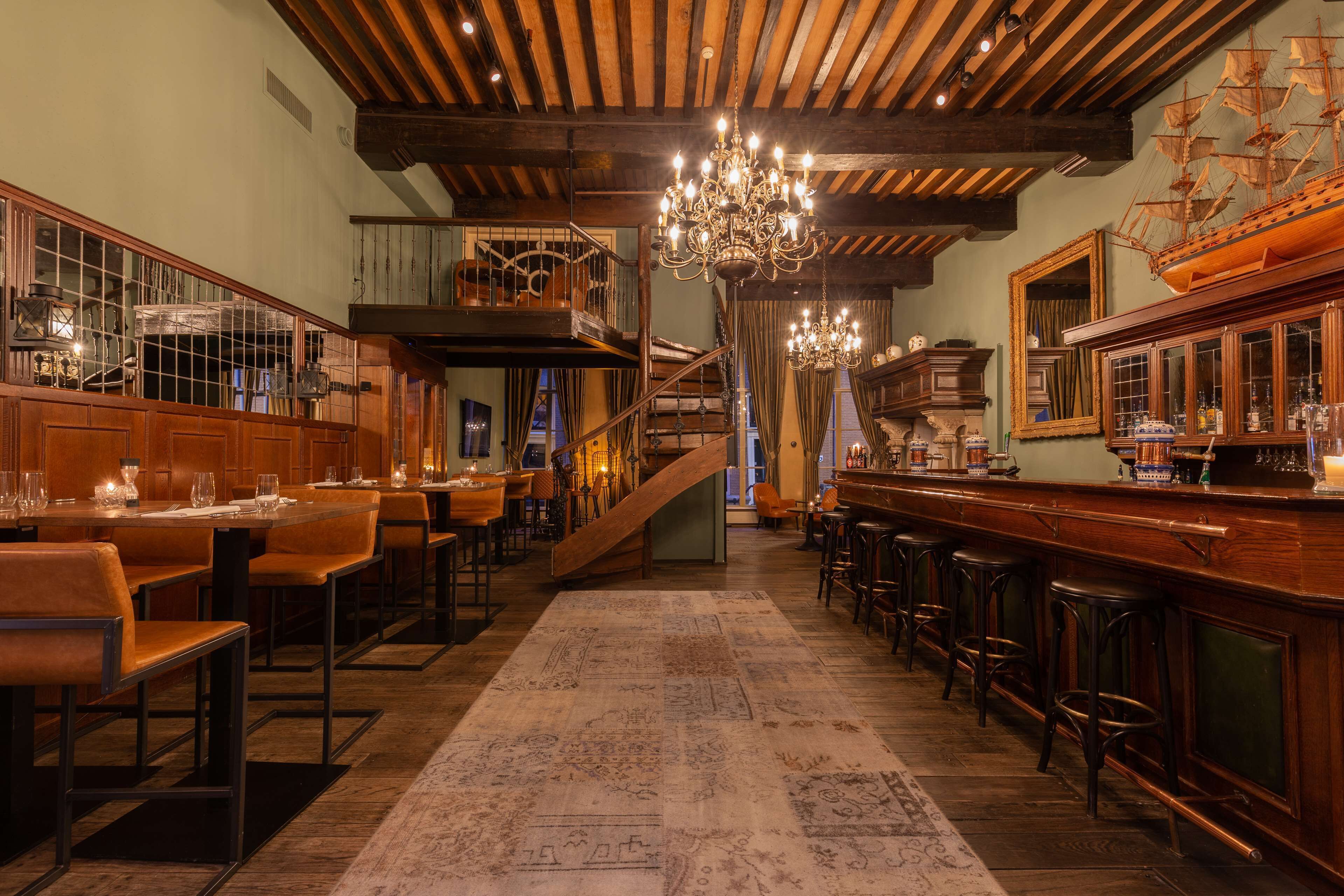 A bar area with wooden furniture, a chandelier, and a ship model on the wall.