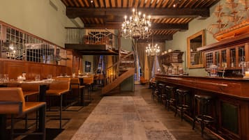 A bar area with wooden furniture, a chandelier, and a ship model on the wall.