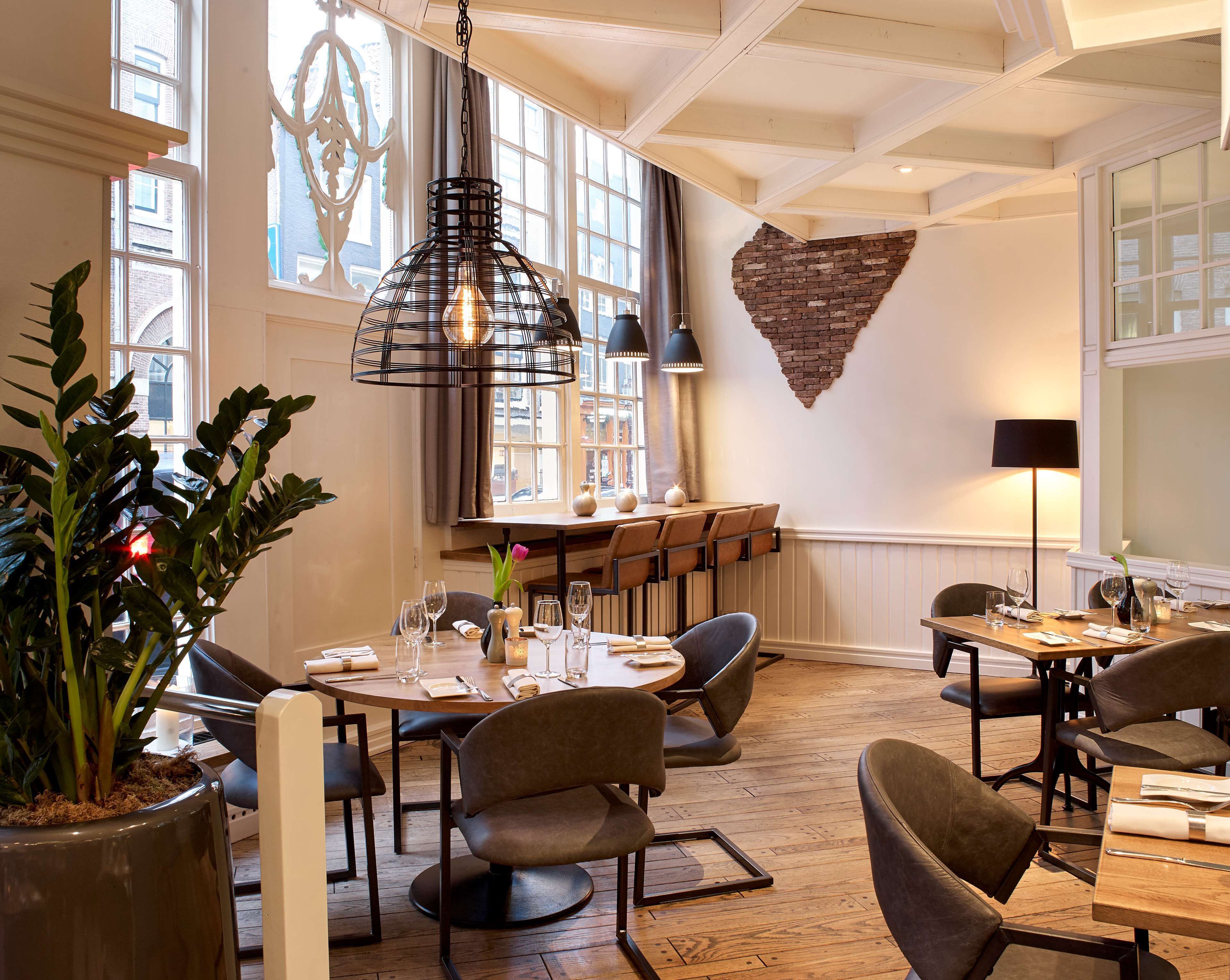 A dining area with round tables, chairs, and hanging pendant lights.