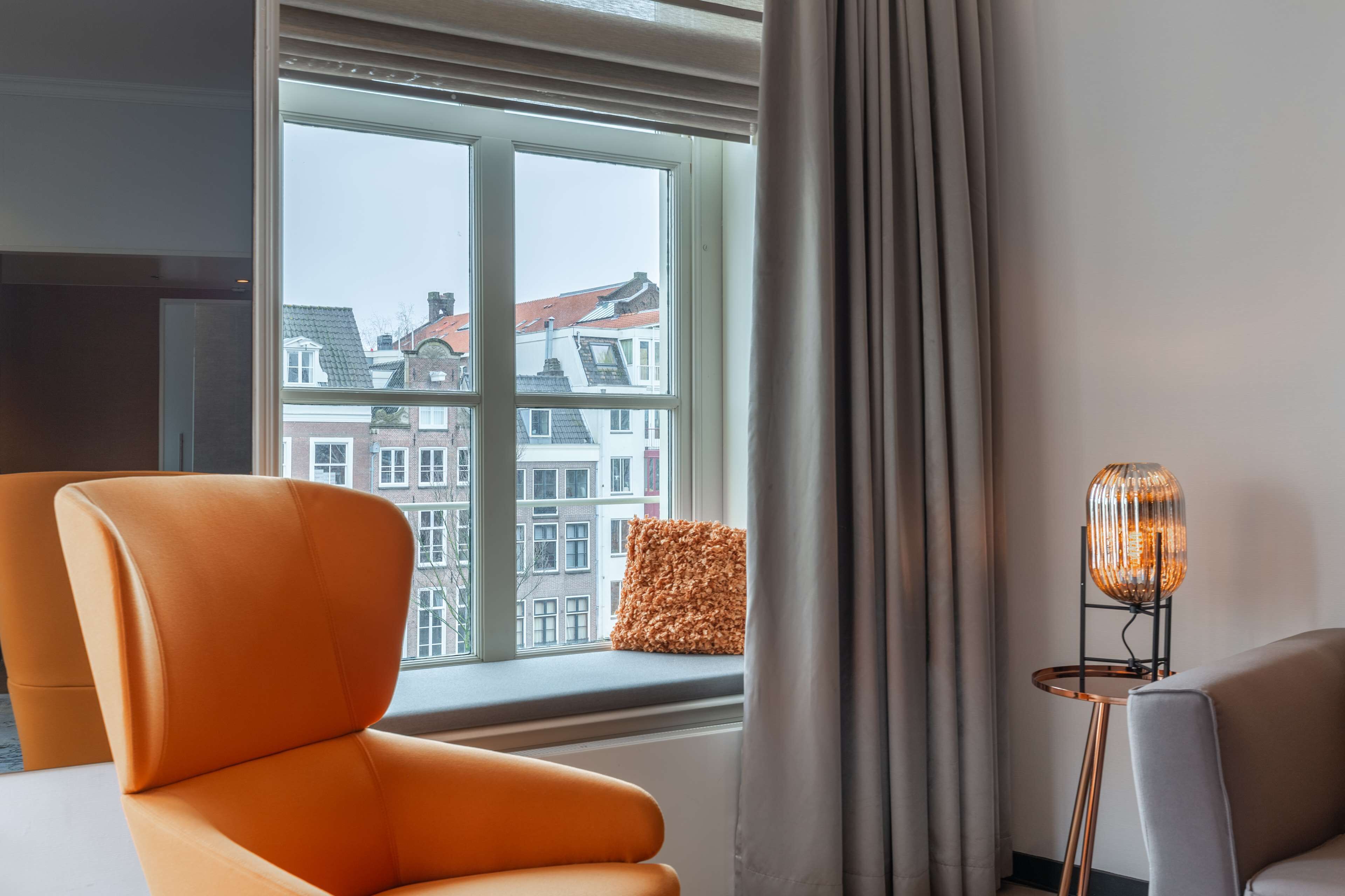Ein modernes Zimmer mit großem Fenster, einer Couch und einer Stehlampe.