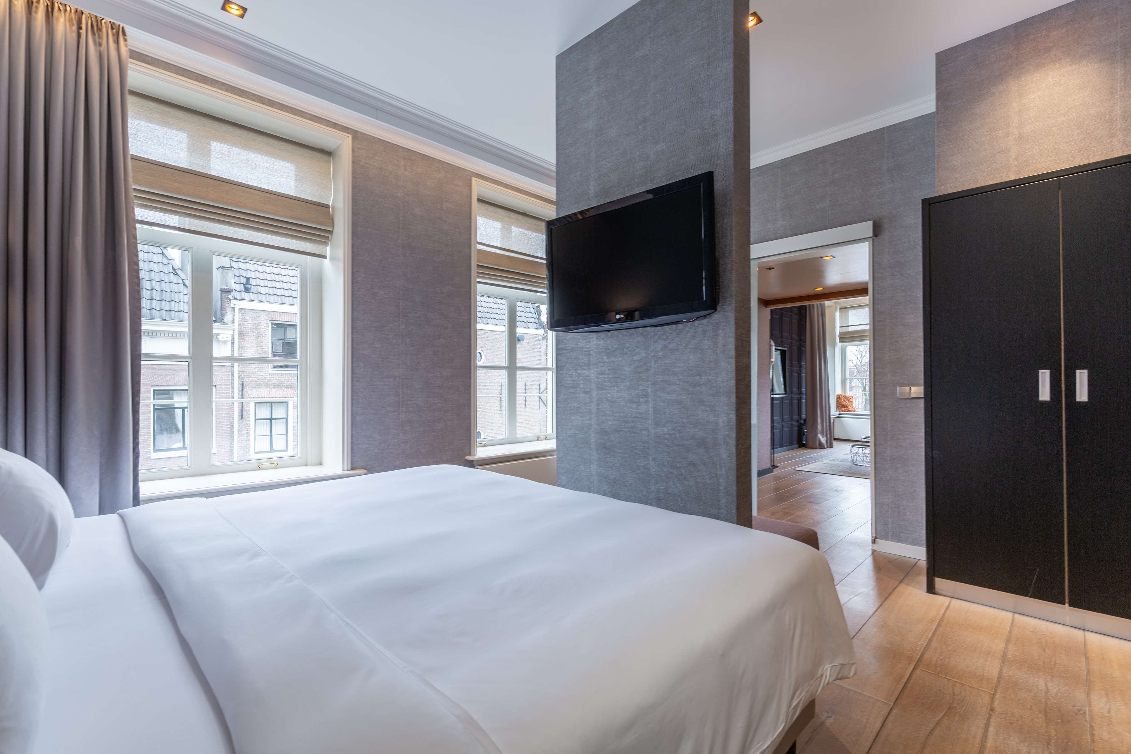 A hotel room with a large bed, a flat-screen TV mounted on the wall, and a wardrobe.