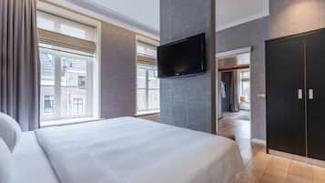 A hotel room with a large bed, a flat-screen TV mounted on the wall, and a wardrobe.