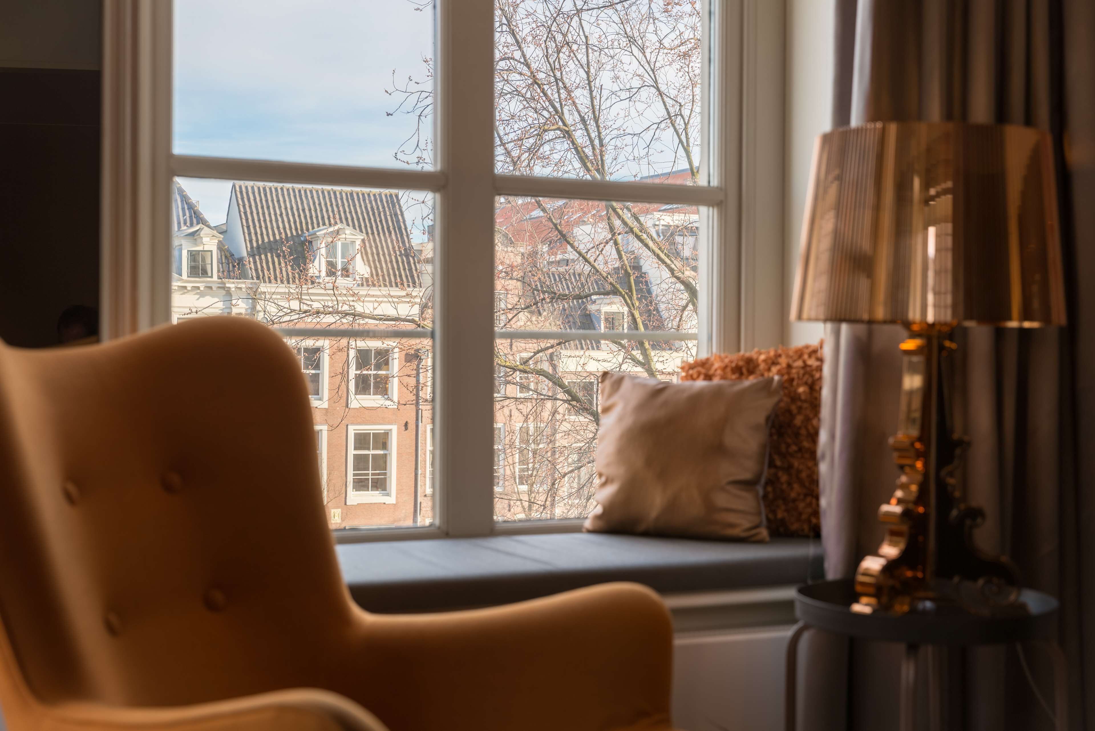 A room with a large window, a sofa, and a lamp.