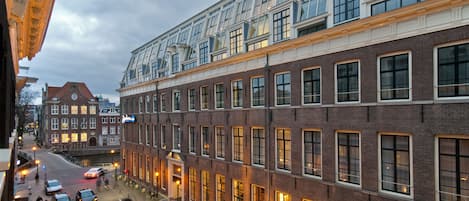A multi-story building with a mix of brick and glass facades, large windows, and a prominent upper section with a glass roof.