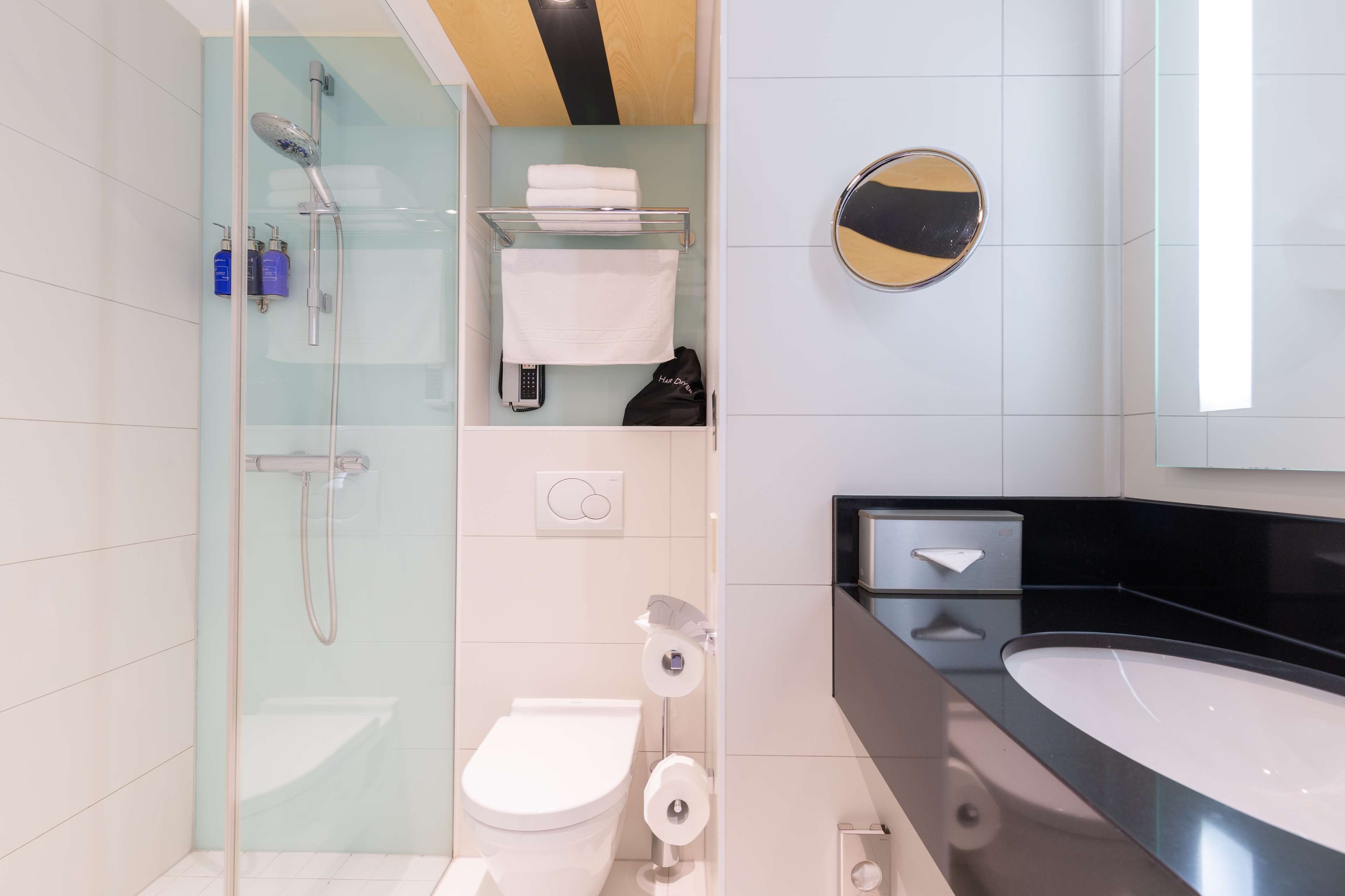 Ein modernes Badezimmer mit einer Duschkabine, einer Toilette, einem Waschbecken und einem Spiegel.