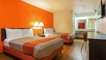 A hotel room with two beds, a desk, a chair, and a TV.