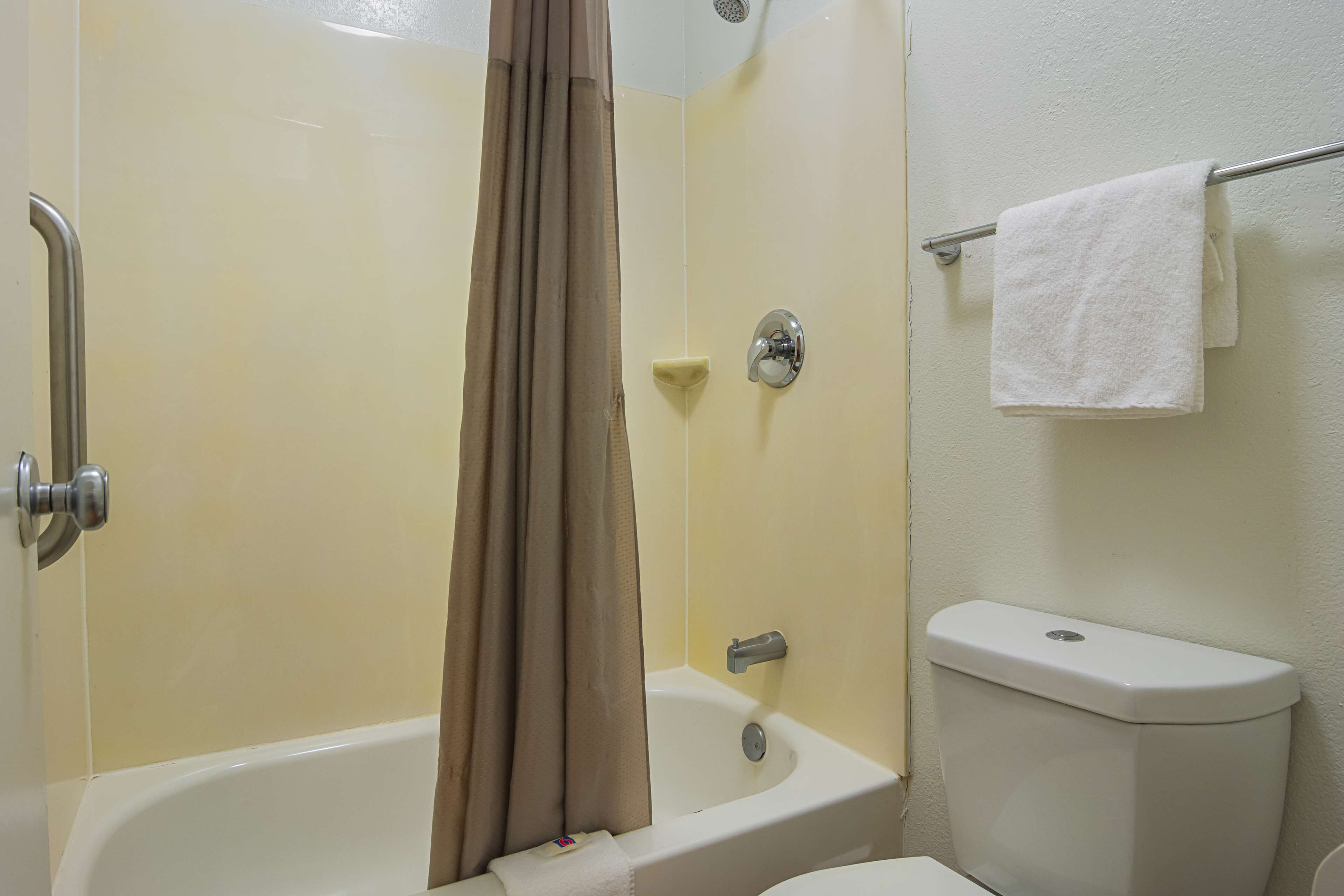 A bathroom with a bathtub, toilet, and towel rack.