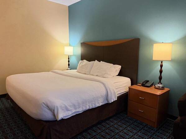 Una habitación de hotel con una cama grande, dos lámparas de noche, un teléfono y una mesita de noche de madera.