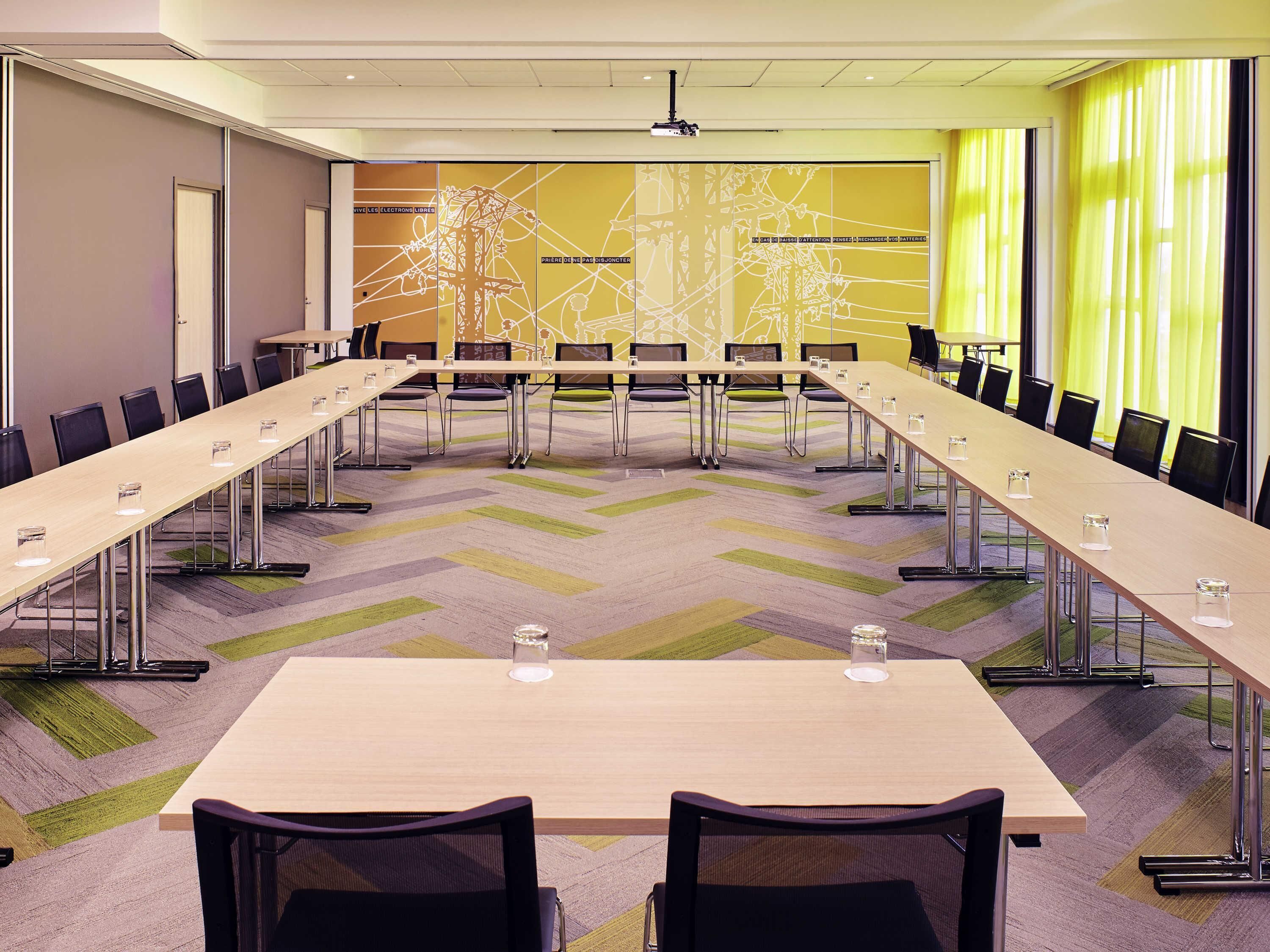 Une salle de conférence équipée d’une longue table, de chaises et d’un écran de projection.