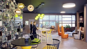 A modern hotel lobby with a tech-themed wall, a reception desk, and seating areas. - Mercure Paris Sud Les Ulis (Les Ulis)