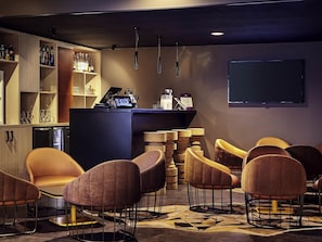 Eine Bar mit einer Theke, Barhocker und einem Fernseher.
