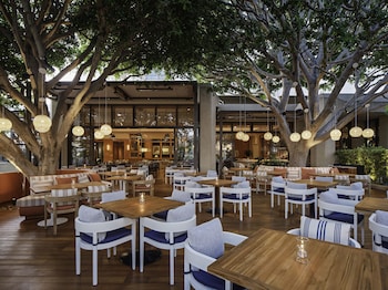 A bar area with a bar counter, seating, and a staircase leading up to it. at Pendry Newport Beach