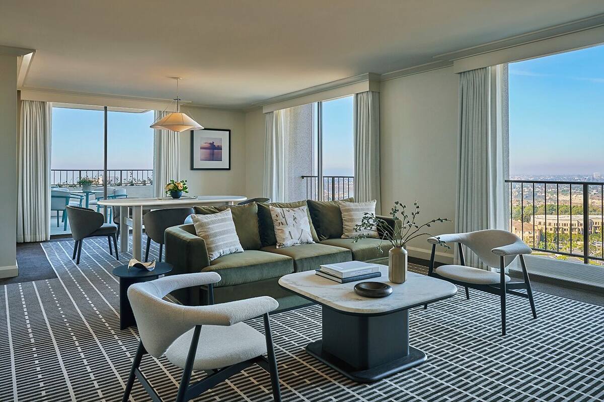 A modern living room with a sofa, chairs, a coffee table, and a view of the city through large windows.