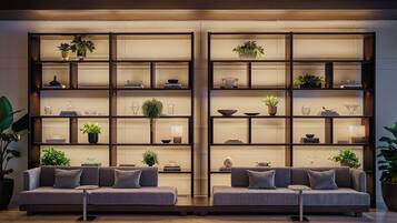 A modern living room with two sofas, a coffee table, and a large bookshelf with decorative items and plants.