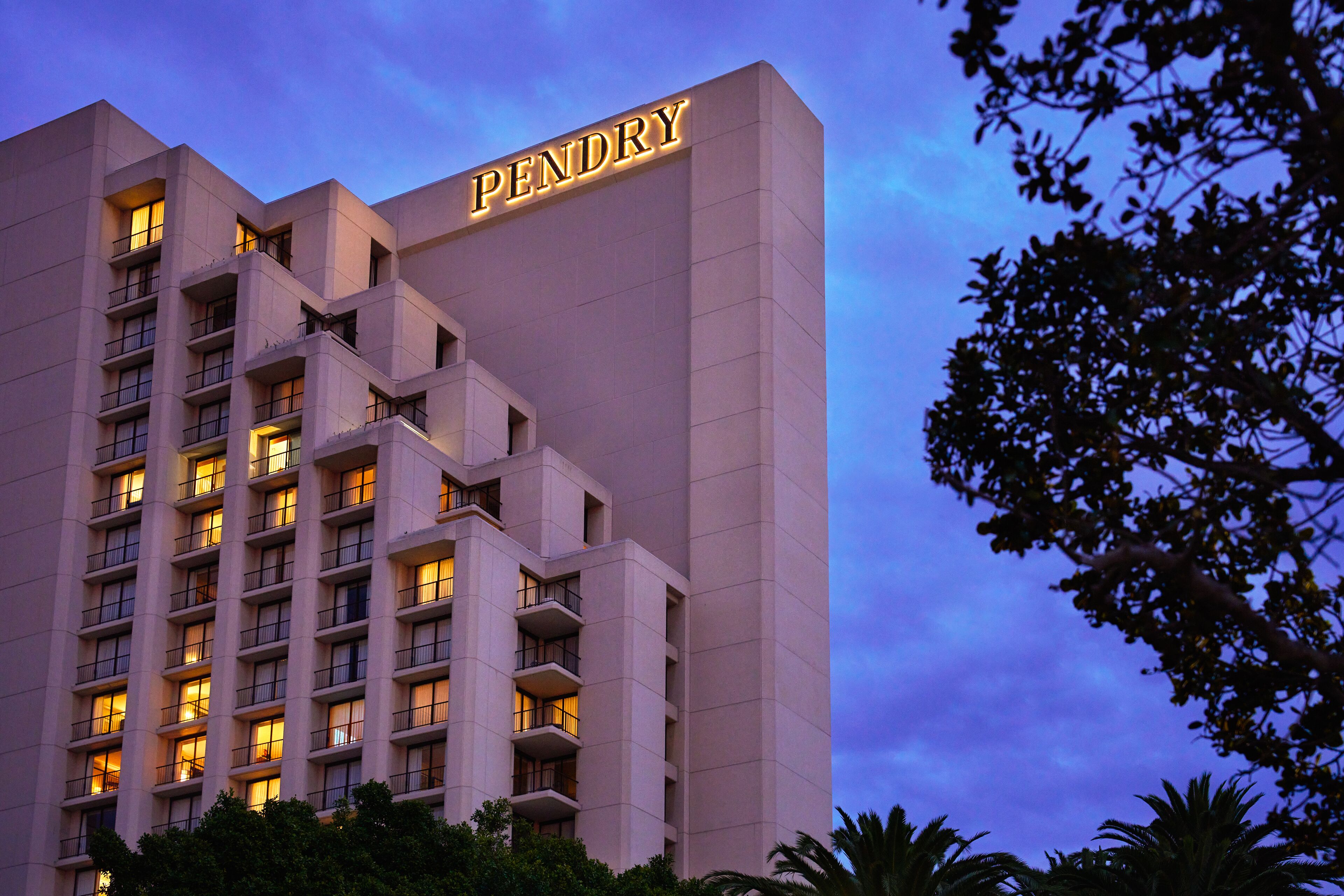 Ein mehrstöckiges Hotel mit beleuchteter Beschilderung mit dem Schriftzug "PENDRY".