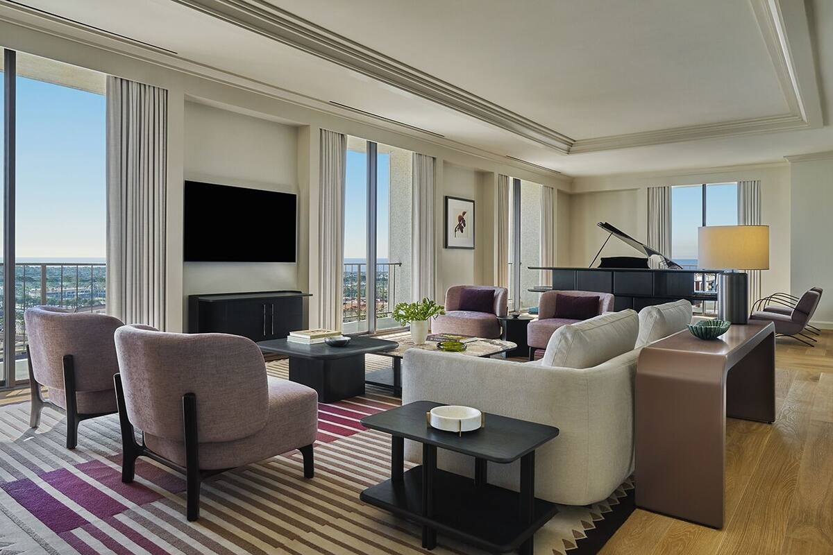 A spacious living room with a large flat-screen TV, a piano, and a comfortable seating area with sofas and armchairs.