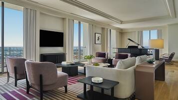 A spacious living room with a large flat-screen TV, a piano, and a comfortable seating area with sofas and armchairs.