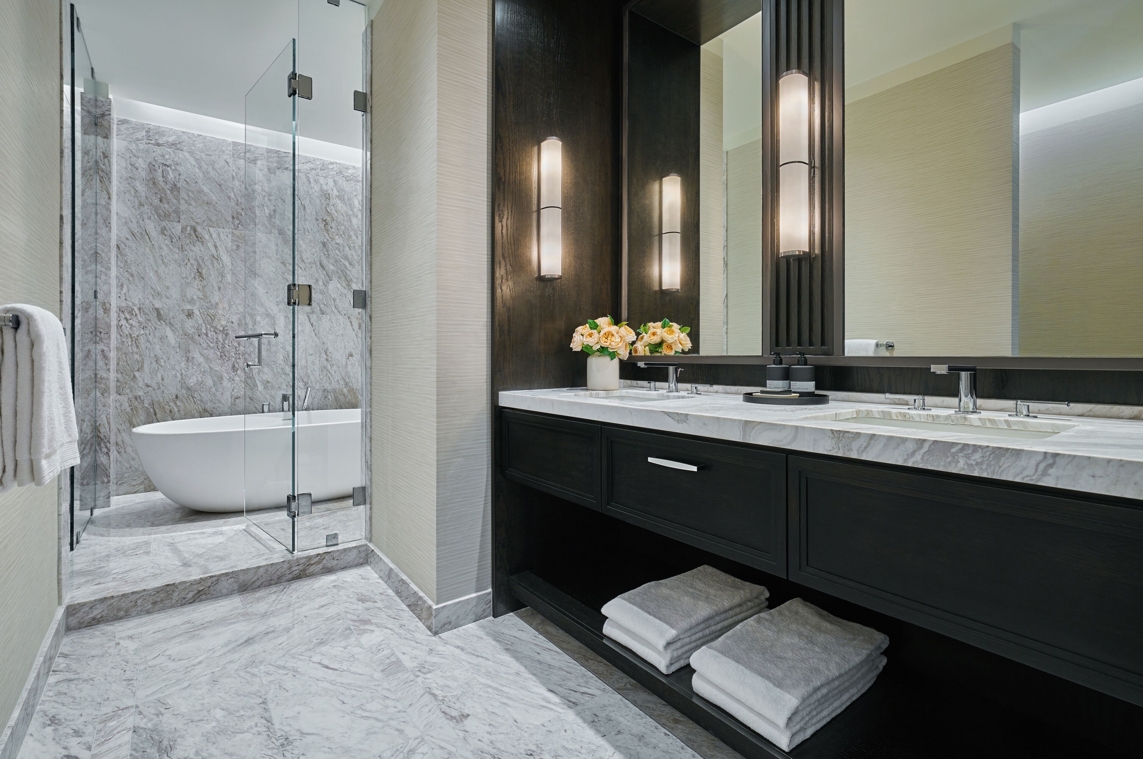 A modern bathroom with a freestanding bathtub, a large mirror, and a vanity with a sink.