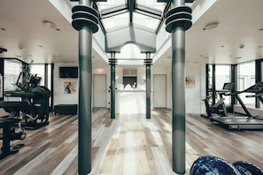 Un gimnasio con equipamiento de ejercicio, mostrador de recepción y tragaluz.