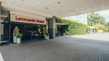 The entrance of the Leonardo Hotel with a paved driveway leading to the entrance.