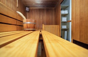 A sauna room with wooden benches and a wooden bucket. - Leonardo Frankfurt City South (Frankfurt)