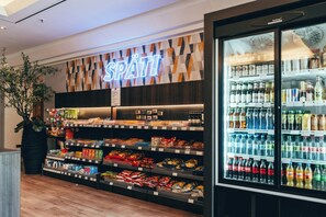 A store interior with a neon sign, shelves stocked with snacks, and a refrigerated display. - Leonardo Frankfurt City South (Frankfurt)