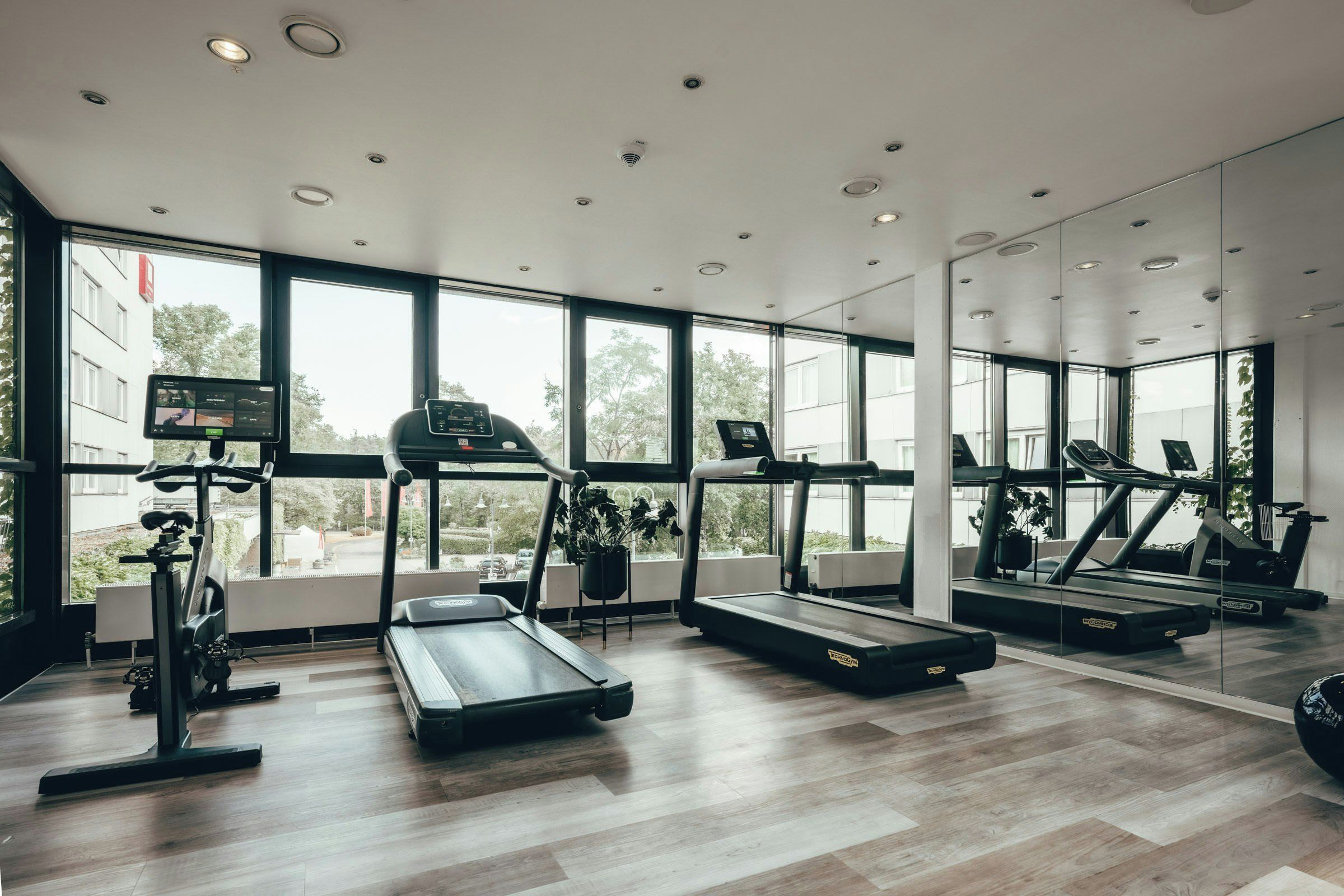 Un gimnasio moderno con cintas de correr, bicicletas estáticas y un espejo grande.