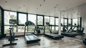 Ein modernes Fitnessstudio mit Laufbändern, Ergometer und einer Spiegelwand.