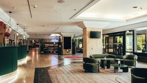Un hall espacioso con mostrador de recepción, zona de estar y un amplio ventanal con vistas al exterior.