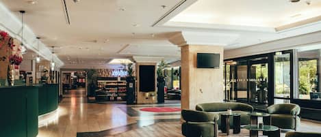 Un hall espacioso con mostrador de recepción, zona de estar y un amplio ventanal con vistas al exterior.
