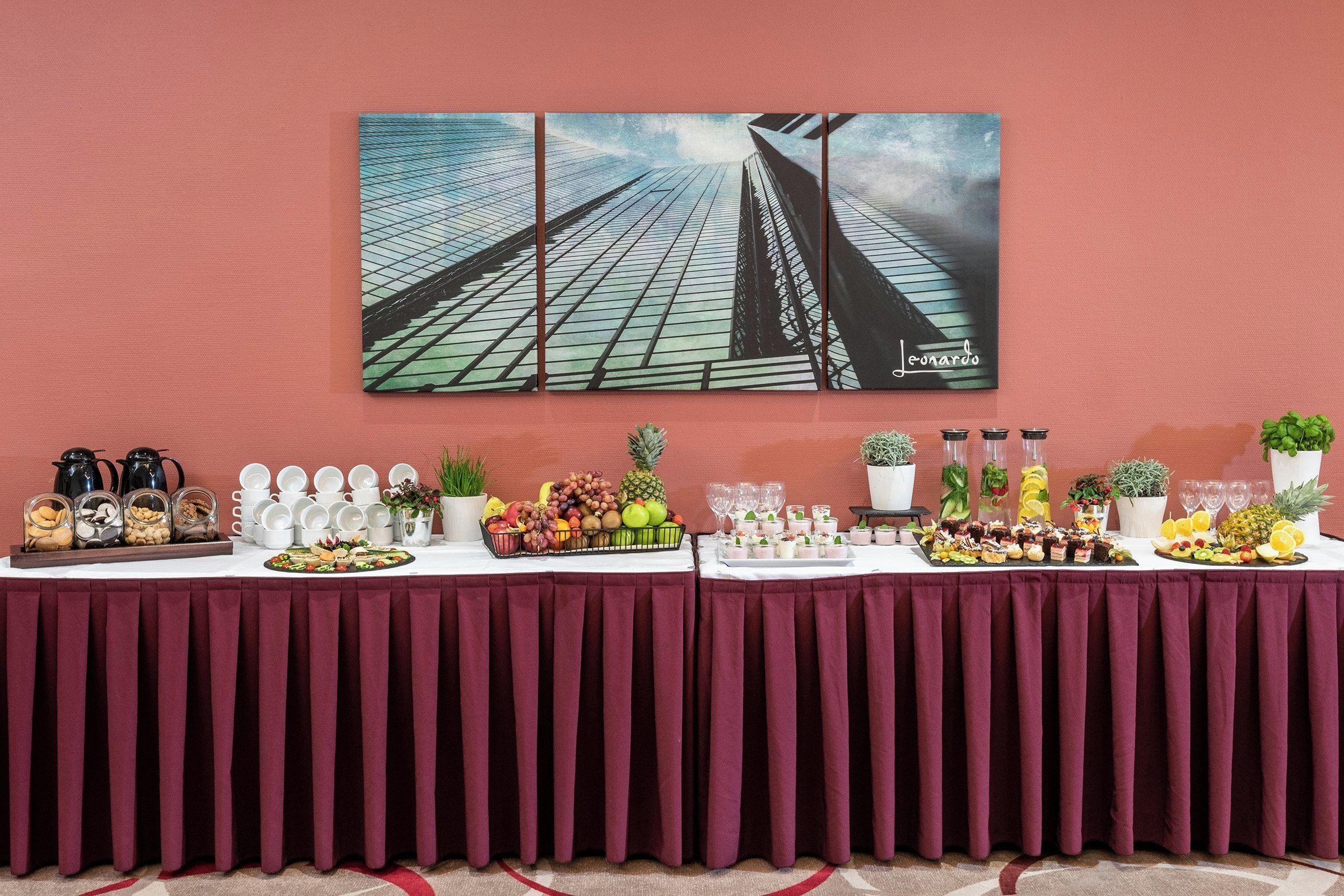 Ein Buffet mit verschiedenen Speisen und dahinter ein Gemälde von Wolkenkratzern an der Wand.