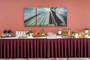 A buffet table with various food items and a painting of skyscrapers on the wall behind it. - Leonardo Frankfurt City South (Frankfurt)