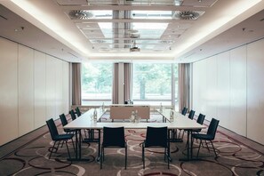 A conference room with a long table, chairs, and a view of trees through large windows. - Leonardo Frankfurt City South (Frankfurt)