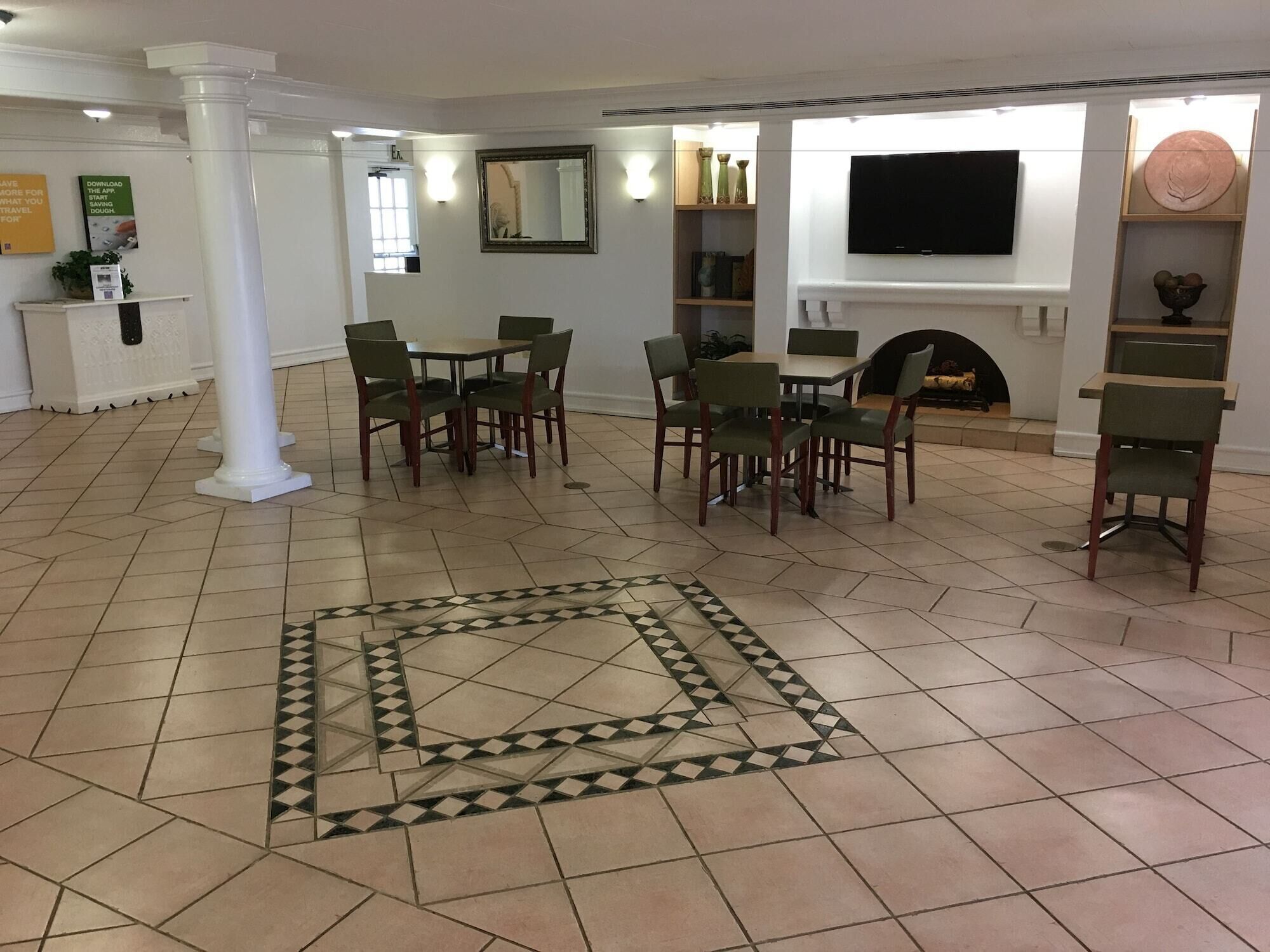 A spacious living area with a fireplace, a television mounted on the wall, and a patterned floor.