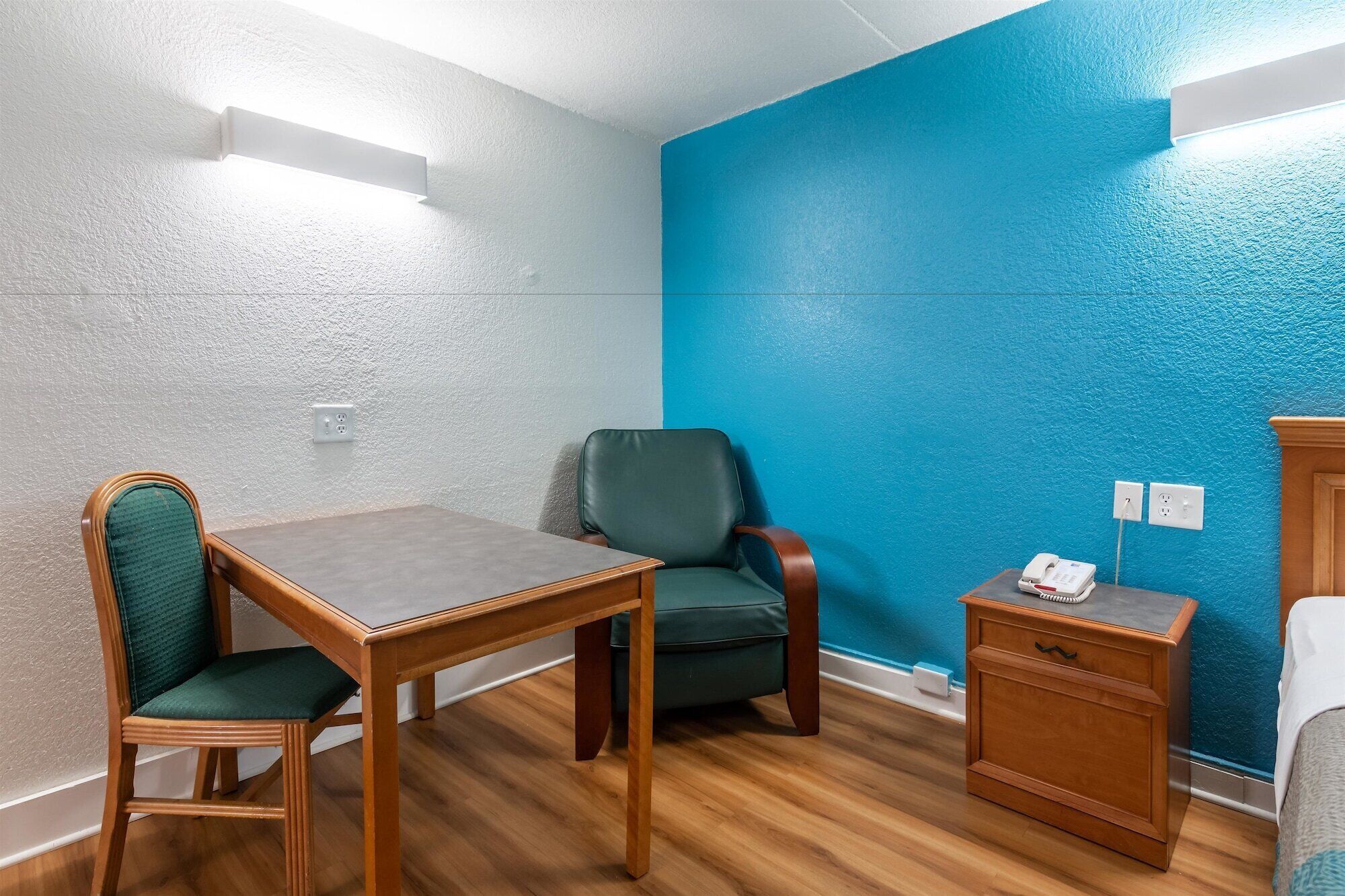 A room with a wooden table and chairs, a blue accent wall, and a telephone on a small wooden cabinet.