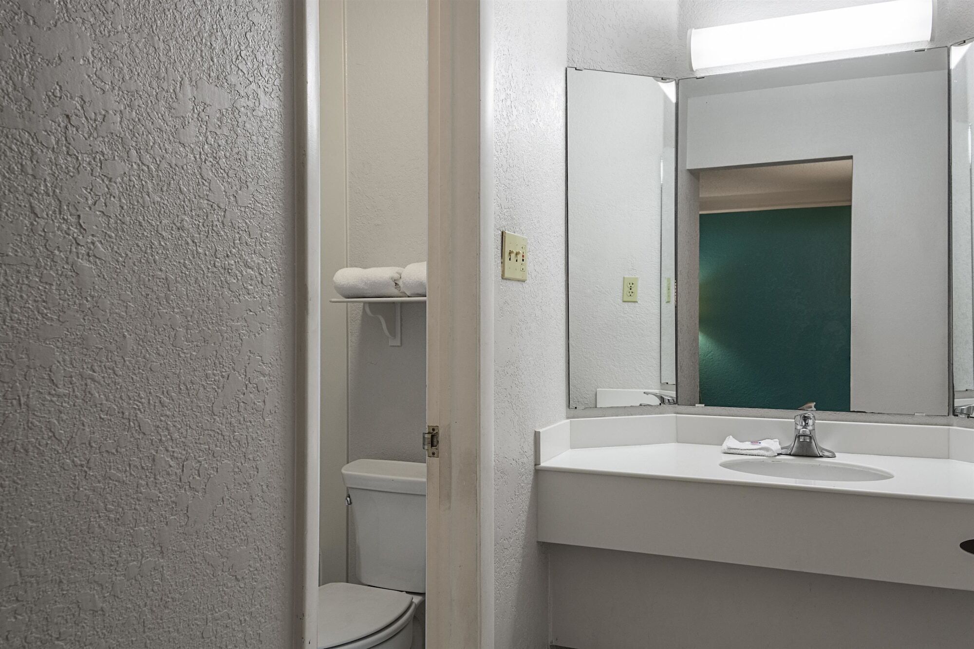 Un baño con un lavamanos blanco, un espejo y un inodoro.
