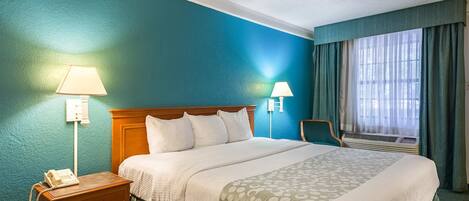 Ein Hotelzimmer mit Bett, Nachttischen, Lampen, Telefon und einem Vorhangfenster.