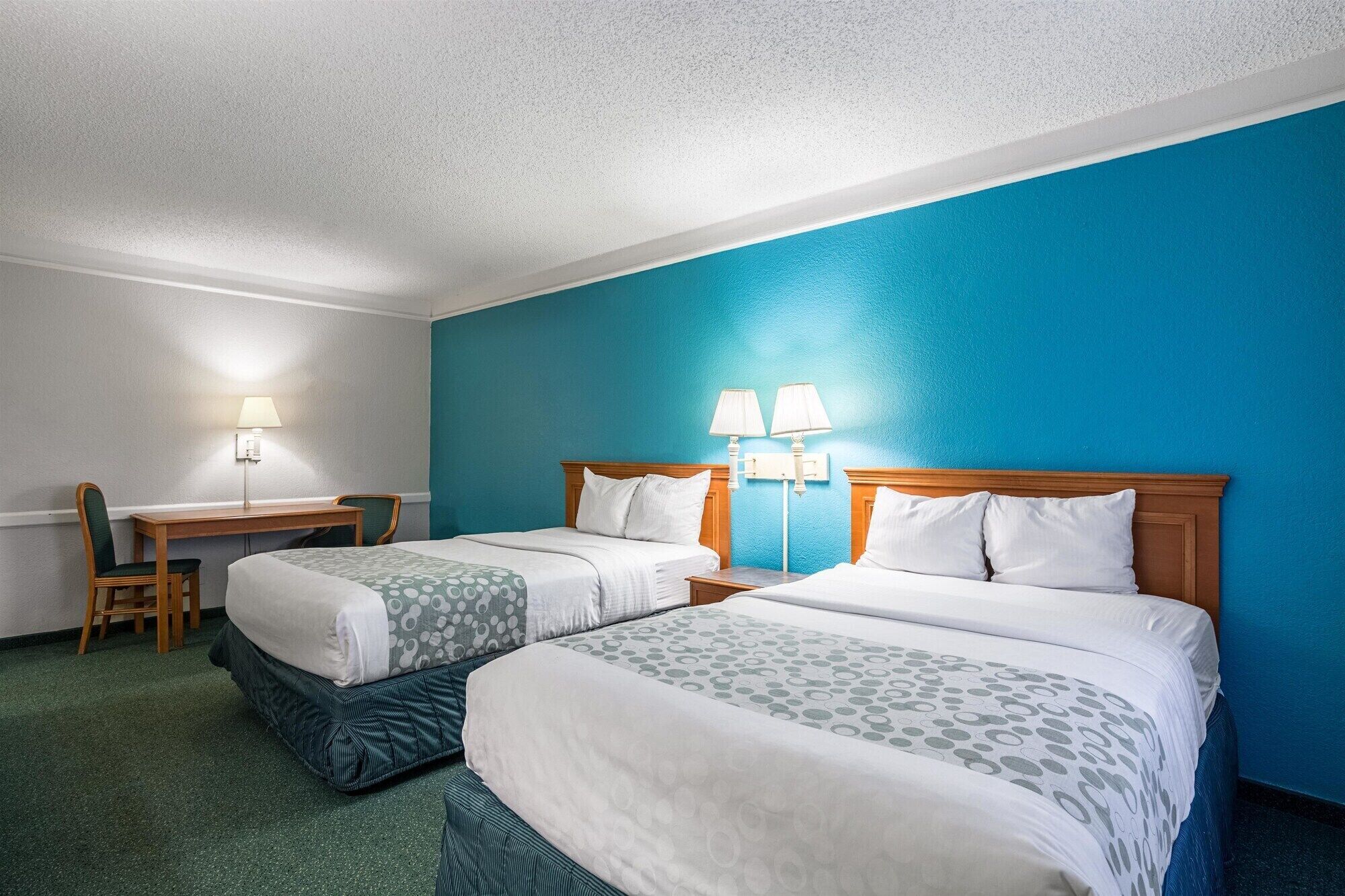 Une chambre d’hôtel avec deux lits, un bureau et une chaise.