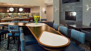 Un vestíbul d'hotel modern amb un taulell de recepció llarg, zona de seients i un bar.